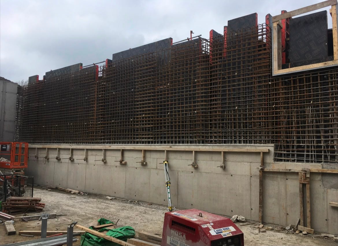 Concrete retaining walls with formwork and crane on site