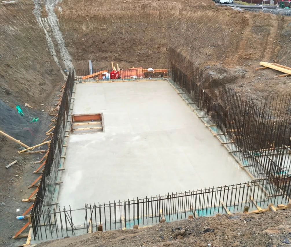 Concrete formwork structure with excavator in background