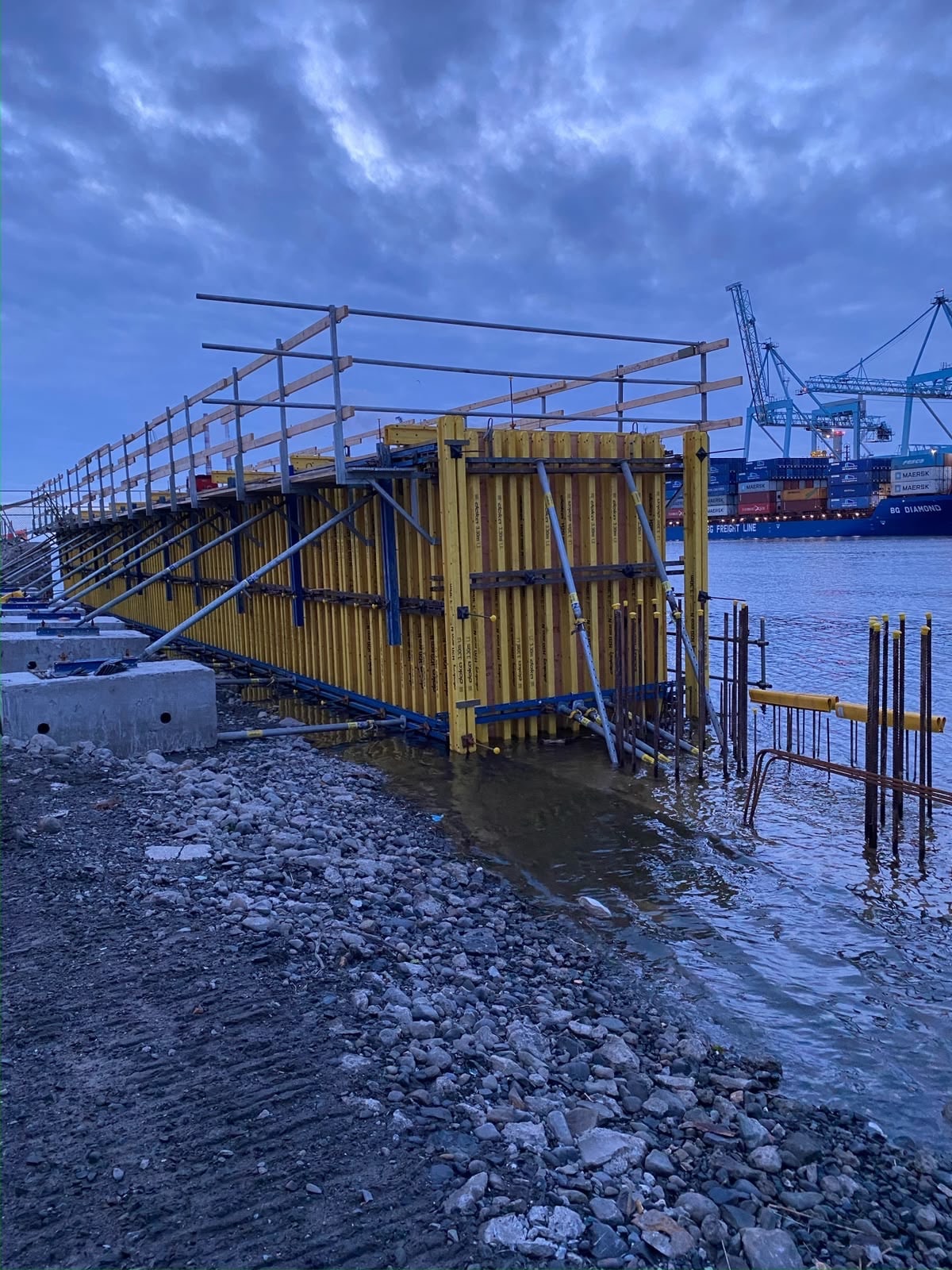 Yellow formwork panels at waterfront port construction site at dusk