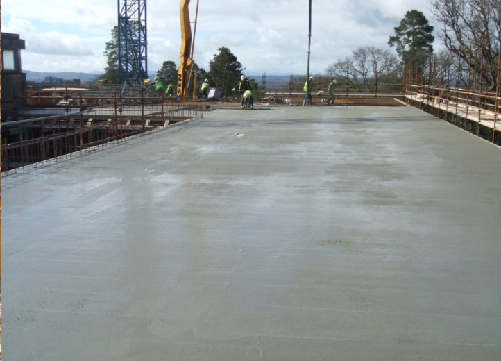 Freshly poured concrete slab with crew finishing surface on elevated structure